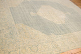 Distressed Tabriz rug corner, showing palmette floral border in dusty blue and ivory.