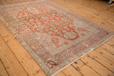 High-angle perspective of a distressed vintage Baktiari rug with a red and blue geometric pattern.