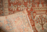 A folded corner of the vintage Bakhtiari rug displays the hand-knotted weave and machine bound edge.