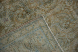 Folded corner of distressed Hamadan rug, revealing woven foundation and machine-bound edge.