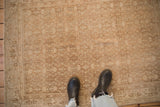 Close view of a distressed Persian Bijar rug's mostly even wear and sandy Herati pattern.
