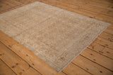 Angled view of a distressed Bijar rug showing the even wear on its beige Herati pattern.