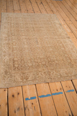 High angle view of a vintage Bijar rug highlighting abrashes across its distressed, sandy-toned Herati design.