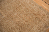 Corner detail of a distressed Bijar rug showing its low pile and muted Herati pattern.