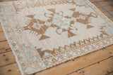 Angled corner view of a distressed Hamadan rug showing its worn texture and floral vine border.