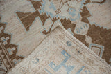 Corner of a distressed Hamadan rug folded to show the hand-knotted back and machine-bound side.