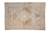 Distressed vintage Hamadan rug with a soft floral medallion in faded beige and ivory, highlighted by navy blue accents.