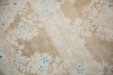 Heavy color abrashes and even wear across the beige and ivory floral pile.
