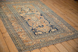 Angled view of an antique Tabriz rug showing its Tree of Life design and intricate scrolling vine borders.
