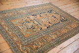 The full length of an antique Tabriz rug, showing time-softened tones across its Tree of Life pattern.