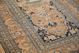 Low pile and floral borders of an antique Tabriz rug in sandalwood, navy, and dusty blue.