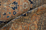 Intricate navy blue scrolling vine border on the time-softened texture of an antique Tabriz rug.
