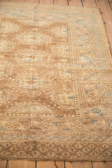 The geometric field and borders of a vintage Afghan rug seen from a low, angled perspective.