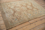 Vintage Afghan rug viewed at an angle, showing geometric motifs and a time-softened pile.