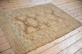 Angled view of a vintage Afghan rug showing its geometric pattern and time-softened low pile.