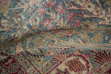 A soft fold revealing the distressed, low pile of a vintage Meshed rug in dusty blue and red.