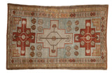 Distressed Caucasian rug with a geometric medallion in rust red and olive on an abrashed powder blue field.