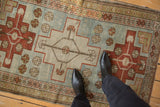 A standing view of the distressed, hand-knotted pile on a vintage geometric Caucasian rug.