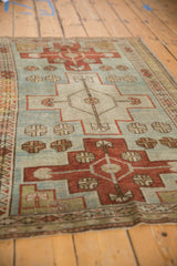 Angled perspective of a vintage distressed rug showing its geometric medallions and low pile.
