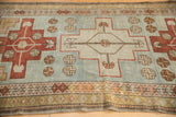 A vintage Caucasian rug's worn pile and time-softened discoloration near its geometric border.
