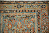 Corner view of a distressed Malayer rug's Herati pattern and geometric border in blue and rust.