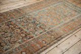 Long perspective showing the time-softened blues, rust, and charcoals of a distressed Malayer runner.