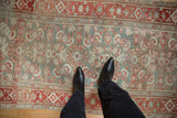 A personal perspective of the distressed Persian rug showing its mostly even wear and Herati design.