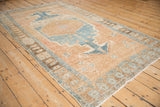 Distressed vintage Northwest Persian rug showing textured pile, geometric border, and scattered plant motifs.