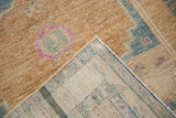 Distressed sandy pile of vintage Persian rug with machine-bound edge and visible woven foundation.