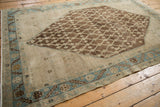 Distressed Hamadan rug corner, highlighting abrashed ivory ground and sky blue serrated border.