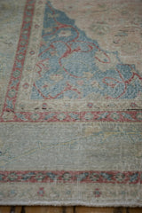 Distressed pale rose border and dusty denim blue field with scrolling vines on a vintage Sivas carpet.