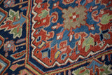 Sharp serrated contours and scrolled vines in brick red and navy blue on a vintage Persian Heriz carpet pile.