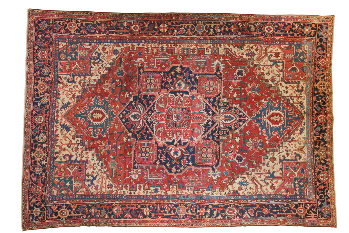 Vintage Heriz carpet with a geometric quatrefoil medallion in cherry red, navy blue, and sand.