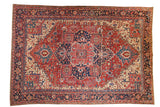 Vintage Heriz carpet with a geometric quatrefoil medallion in cherry red, navy blue, and sand.