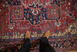 Geometric vines and low pile texture of a vintage Heriz carpet in cherry red and navy blue.