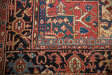 Close-up of the Heriz carpet's main border with geometric turtle samovar motifs in navy and red.