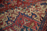 Hand-knotted texture of a vintage Heriz carpet with red, blue, and sand geometric designs.