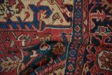 Close-up on the hand-knotted pile of a vintage Heriz, showing red, navy, and sand geometric details.