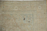 Worn beige pile with faded seafoam patterns and visible foundation on a distressed Sarouk rug corner.