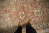 Distressed vintage Anatolian rug with faded ruby red geometric starburst motifs and even wear.