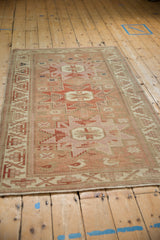 Anatolian rug, distressed starburst medallion, geometric motifs, worn pile, pale red and ivory tones.