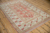 Distressed vintage Melas rug corner, dusty red serrated leaf and serpent motifs.