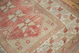 Distressed Melas rug's serrated leaf main border in dusty raspberry and beige.