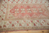 Textured border detail of the vintage distressed Melas rug, highlighting muted red and geometric leaves.
