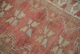 Distressed vintage Melas rug pile, dusty raspberry field, and beige serrated leaf pattern.