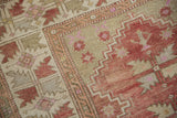 Detail of vintage distressed Melas rug: raspberry, ivory serrated leaf, and zigzag motifs.