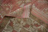 Folded vintage Melas rug corner showing distressed raspberry pile and hand-knotted striped back.