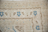 Corner detail of a vintage distressed rug showing its low, worn pile and blue floral border motifs.