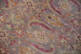 Angled detail of paisley boteh and floral palmettes in magenta and orange on a distressed pile.