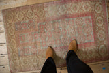 Distressed Belouch rug with faded raspberry floral guls and hook motifs on beige.